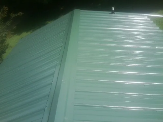 New green metal panels meeting at the ridge of a roof — Flat Roof Repair work by our crew in Woodleaf