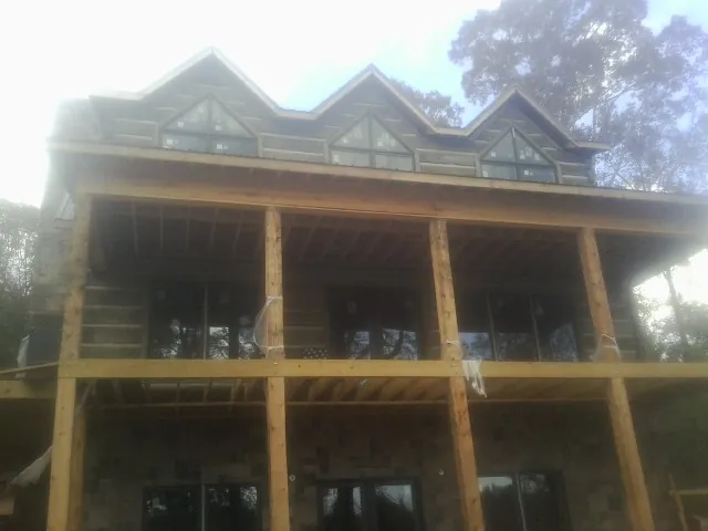 Dormers and porch framing on a large log home under construction — Roof Coating work by our crew in Woodleaf