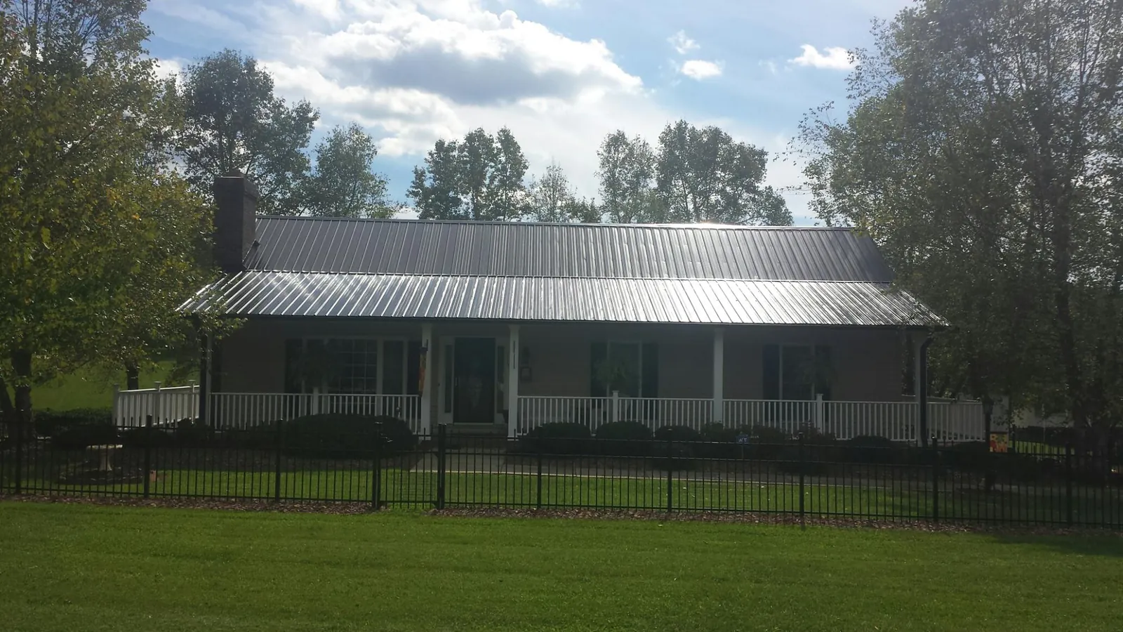 Gray metal roof on a brick ranch with a full width front porch — Gutter Guard Installation work by our crew in Woodleaf