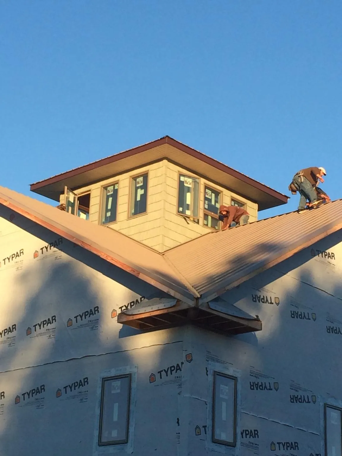 Roofers working around a rooftop cupola on a new metal roof at sunset — Roof Waterproofing in Woodleaf by Roofing Brothers